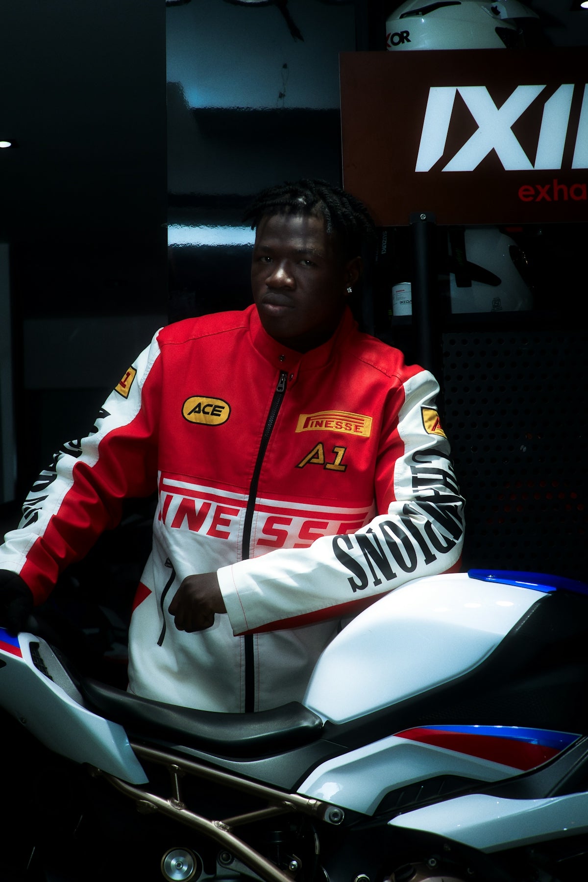 Man in racing jacket leans on motorcycle